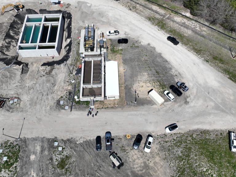 Industrial water treatment facility under construction with large tanks and equipment, aerial view showing construction site, machinery, and parked vehicles.