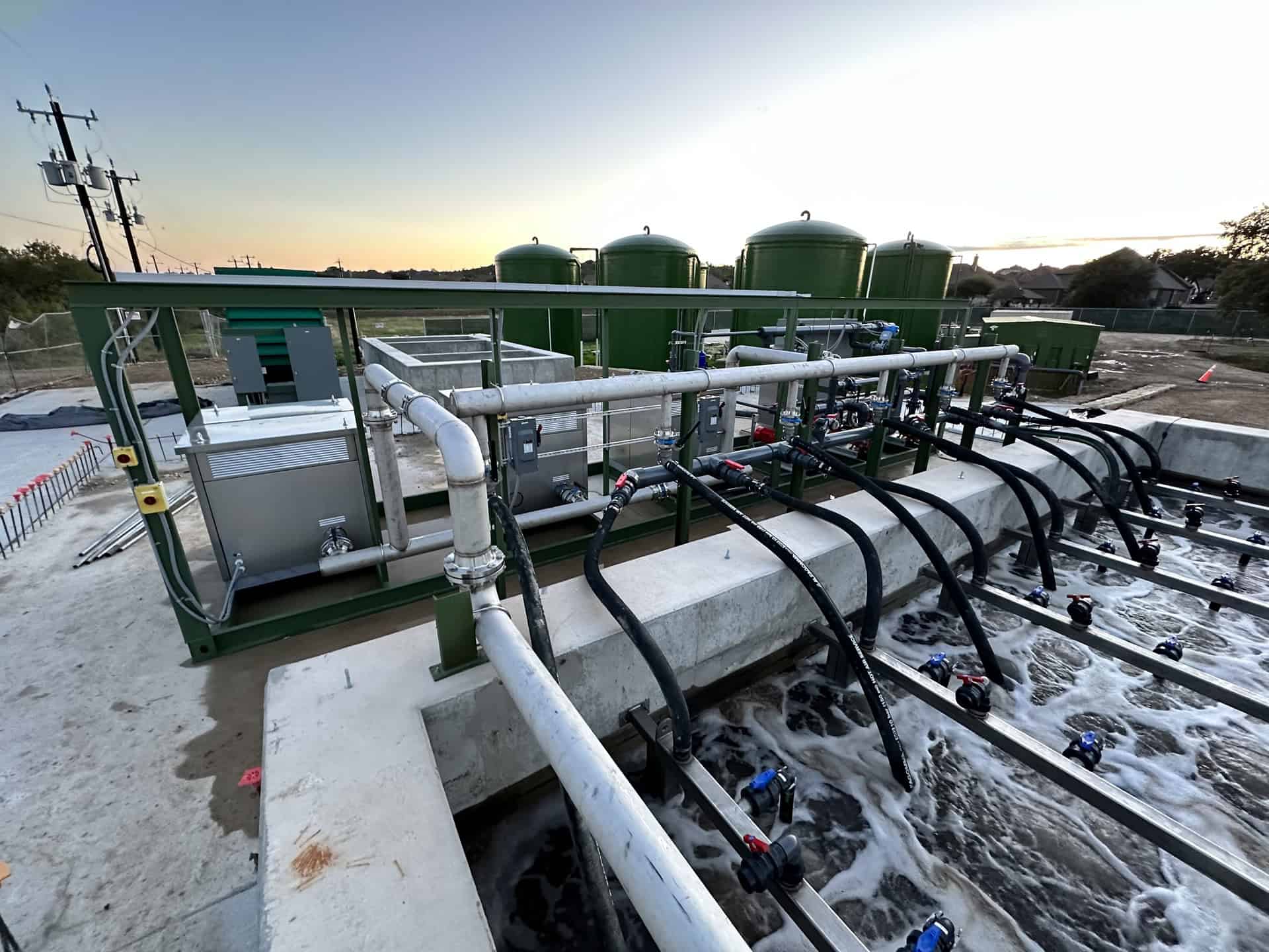 Efficient industrial water treatment system with filtration tanks and piping infrastructure at sunset.